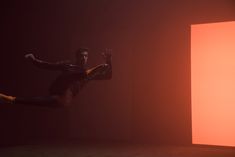 a man is jumping in the air with his arms out and legs spread wide as he appears to be performing an acrobatic dance