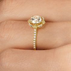 a woman's hand with a yellow diamond ring on her left side and the center stone is surrounded by small white diamonds