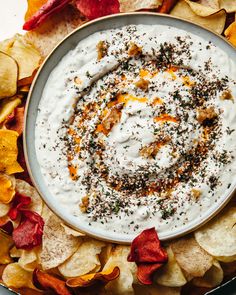 a bowl filled with white dip surrounded by chips