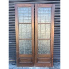 two wooden doors with glass panels in front of a building