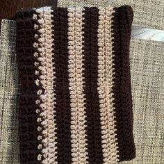 a brown and white crocheted dishcloth on a couch with a wooden table in the background