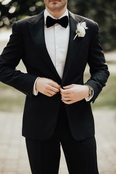 a man in a tuxedo is standing with his hands on his hips and looking at the camera