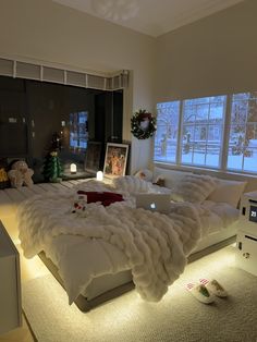 a large bed sitting in the middle of a living room next to a window with christmas decorations on it