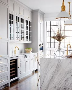 a kitchen with marble counter tops and gold accents on the cabinetry, along with white cabinets