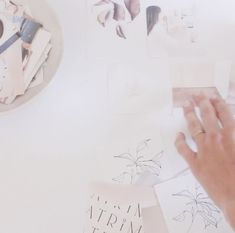 a person's hand on top of some paper with other papers and pictures in the background