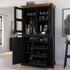 a black cabinet with wine glasses and bottles in it next to a bar stool on the floor