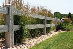 a wooden fence surrounded by grass and rocks