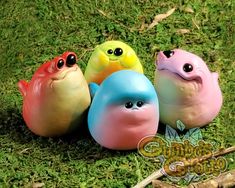 three small plastic birds sitting in the grass