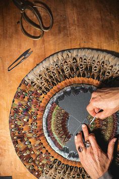 a person is working on a rug with scissors and other crafting supplies next to it