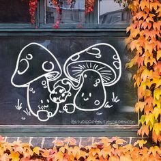 graffiti on the side of a building with leaves around it