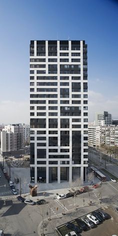 an office building in the middle of a parking lot with lots of cars parked around it