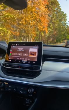 the dashboard of a car with an electronic device in it's center console and trees in the background