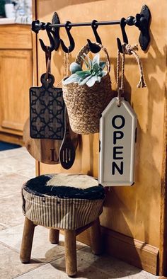 an open sign hanging on the wall next to a potted plant and wooden spoons