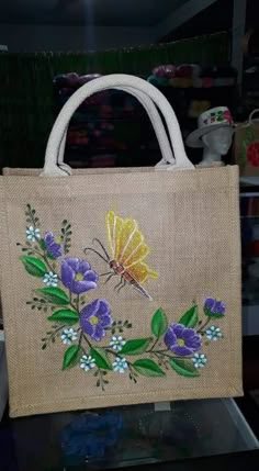 a handbag with flowers and a butterfly on the front is sitting on a table