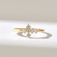 a gold ring with three small diamonds on it's side, sitting on a white surface