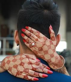 the back of a woman's head with henna tattoos on her arms and hands