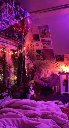 a bedroom with purple lighting and pictures on the wall above it is lit up by string lights