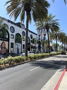 palm trees line the street in front of a building with an advertisement on it's side