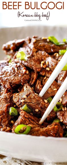 beef and sesame seed stir fry in a white bowl with chopsticks on top