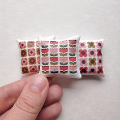 a hand holding two pieces of fabric with flowers on them