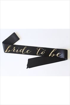 the bride to be sash is black with gold lettering on it and has a satin ribbon