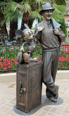 a statue of a man with a mouse on top of a suitcase