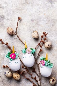 eggs decorated with flowers and unicorn heads are sitting on the ground next to some twigs