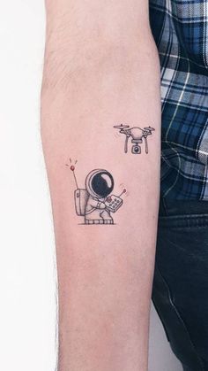 a man's arm with a small tattoo of an astronaut and a flying object