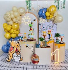 a birthday party with balloons and decorations on the wall, including winnie the pooh cake