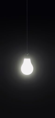 a light bulb hanging from a black ceiling in the dark with only one light on