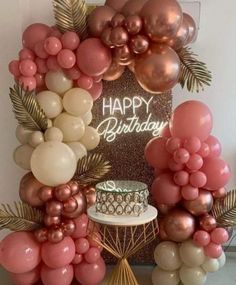 a birthday cake surrounded by balloons and palm leaves