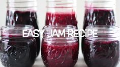 four jars filled with jam sitting on top of a white table next to each other