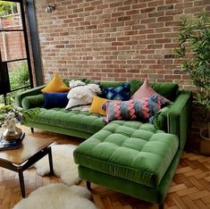 a green couch sitting in front of a brick wall