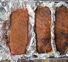 three pieces of meat sitting on top of aluminum foil covered in seasoning and seasoning