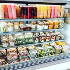 a display case filled with lots of different types of drinks and salads in plastic containers