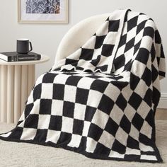 a black and white checkered blanket sitting on top of a chair next to a table