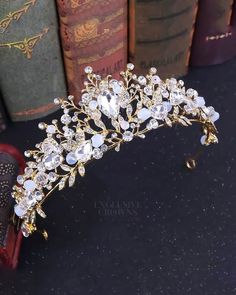 a gold tiara with crystal stones and pearls on the headpiece is displayed in front of books