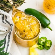 a spoon full of pineapple jam next to some green peppers and jalapenos