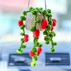 a crocheted plant hanging from a car dashboard