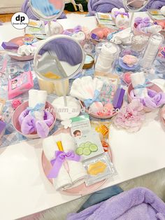 a table topped with lots of different items on top of a white table covered in purple towels