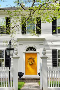 a white house with a yellow front door and wreath on it's side entrance