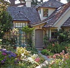 a house that is surrounded by flowers and trees