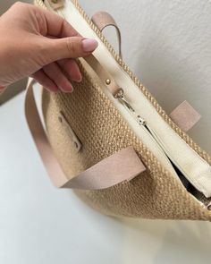 a hand is holding onto a beige purse