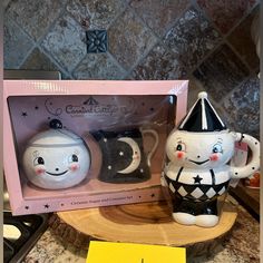 two ceramic teapots in the shape of cats with hats on them, sitting next to each other