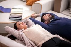 a man and woman laying on top of a couch next to each other