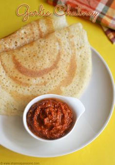 some food is on a white plate and has sauce in a small bowl next to it