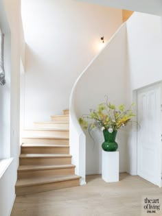 there is a vase with flowers on the table in front of the stairs and door