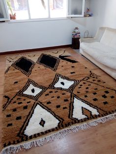 a living room area with a couch and rug on the floor, windows in the background