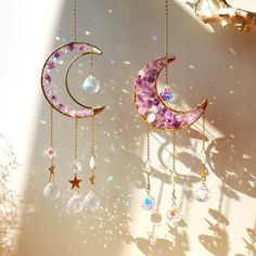 two moon and star mobiles hanging from chains with crystal beads on the sides, against a white background