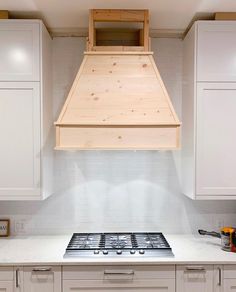 a stove top oven sitting inside of a kitchen under a wooden hood over it's burner